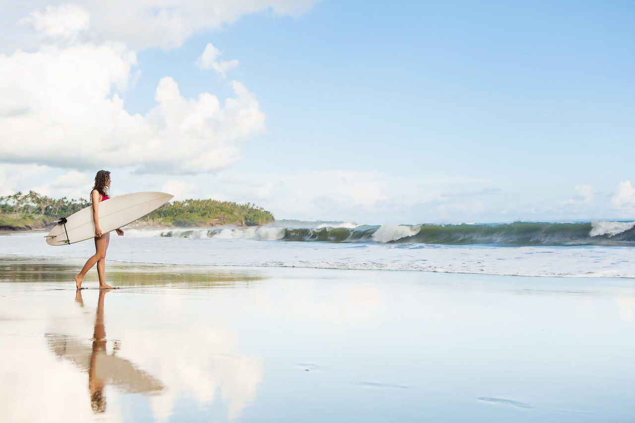 Young lady with surfboard going to the ocean at surf spot