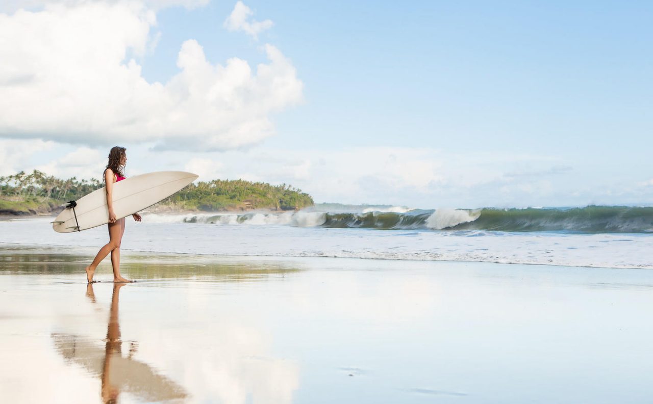 Young lady with surfboard going to the ocean at surf spot